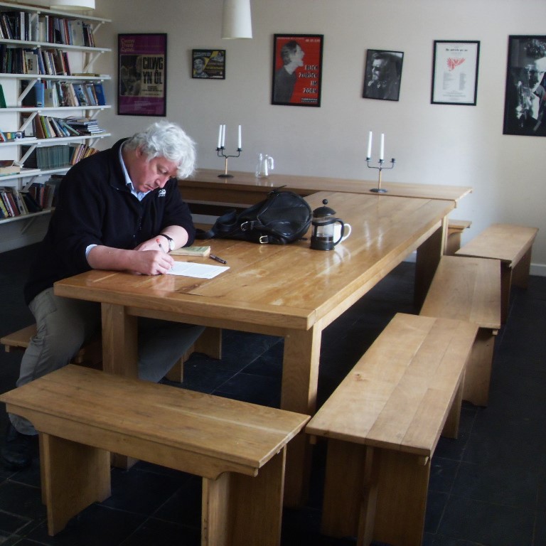A photo of the late writer and critic Kevon Jackson writing at a table at the Hurst writing centre in Shropshire