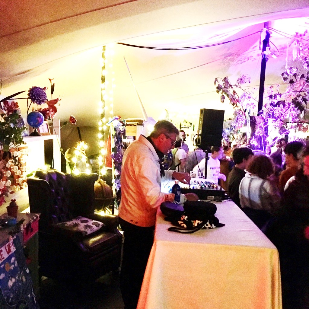 Poet Laureate Simon Armitage peers at a mixing desk where he is DJing a late night party at the Greenbelt Festival