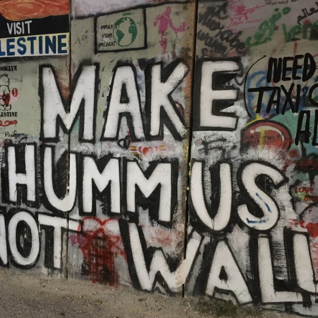 Graffiti on the Israeli defence wall reading 'Make Humus Not Walls'.