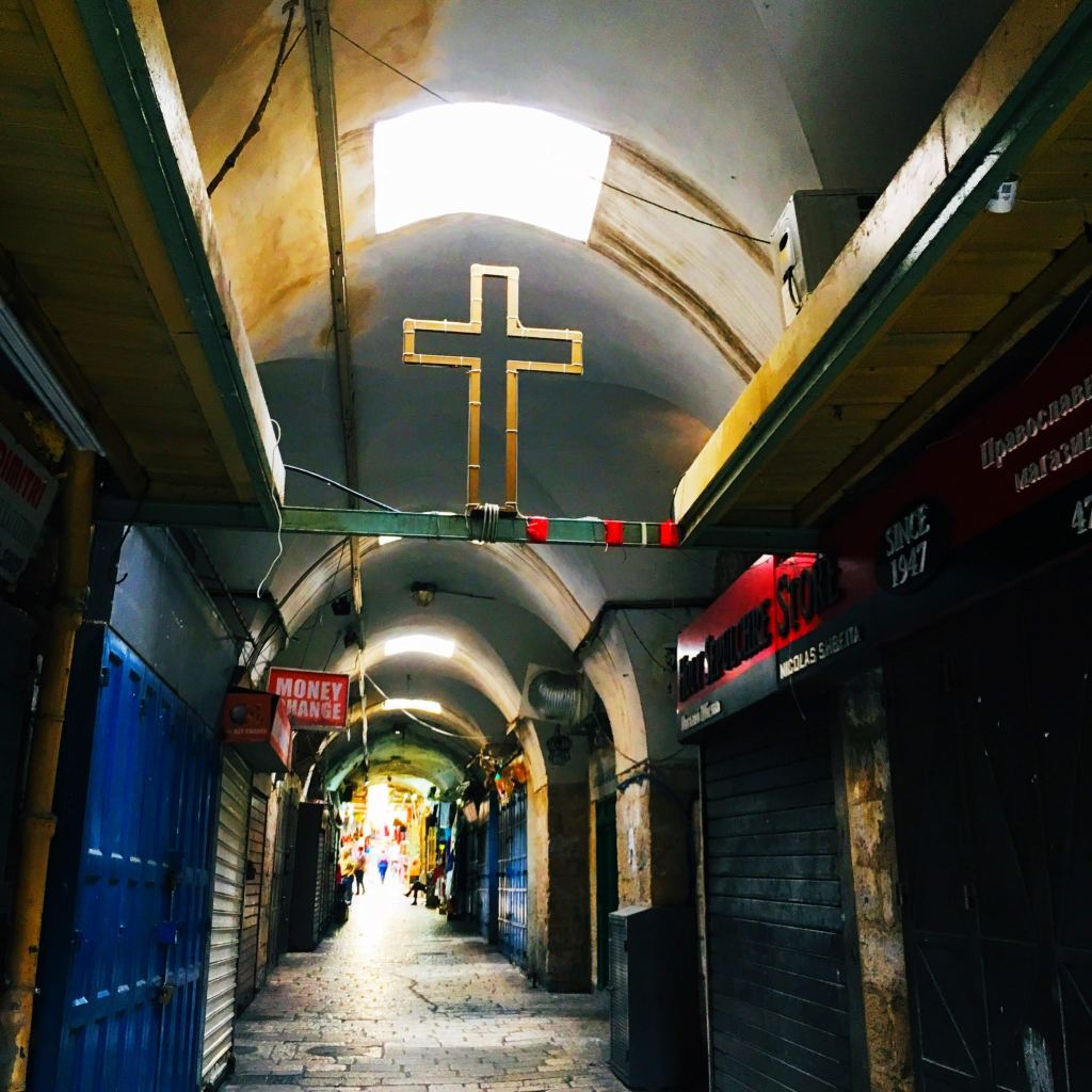 The ceiling of a covered market in Eastern Jerusalem, a metal cross suspended in the space above the passageway.