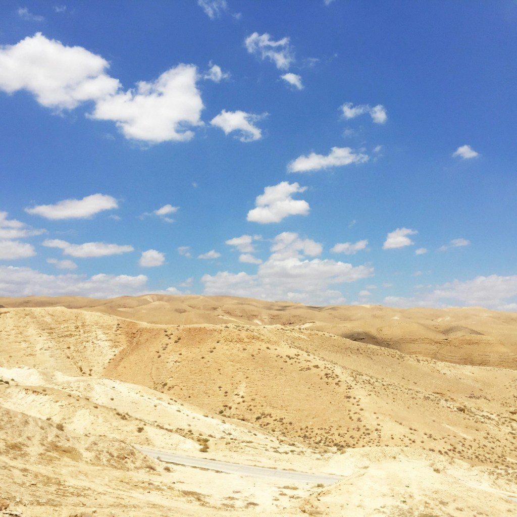 A view of desert hills with blue sky and clouds.