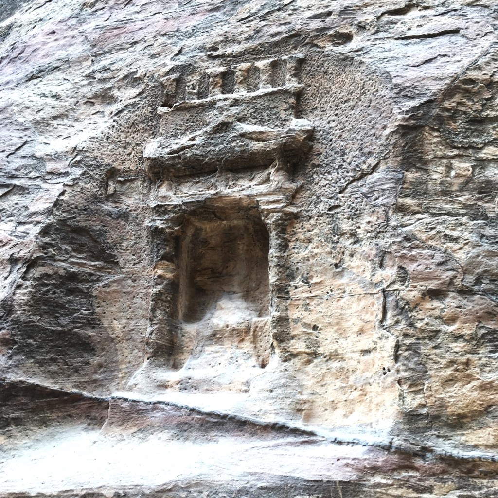 A rock-carving of an ancient doorway with a crenellated balcony.