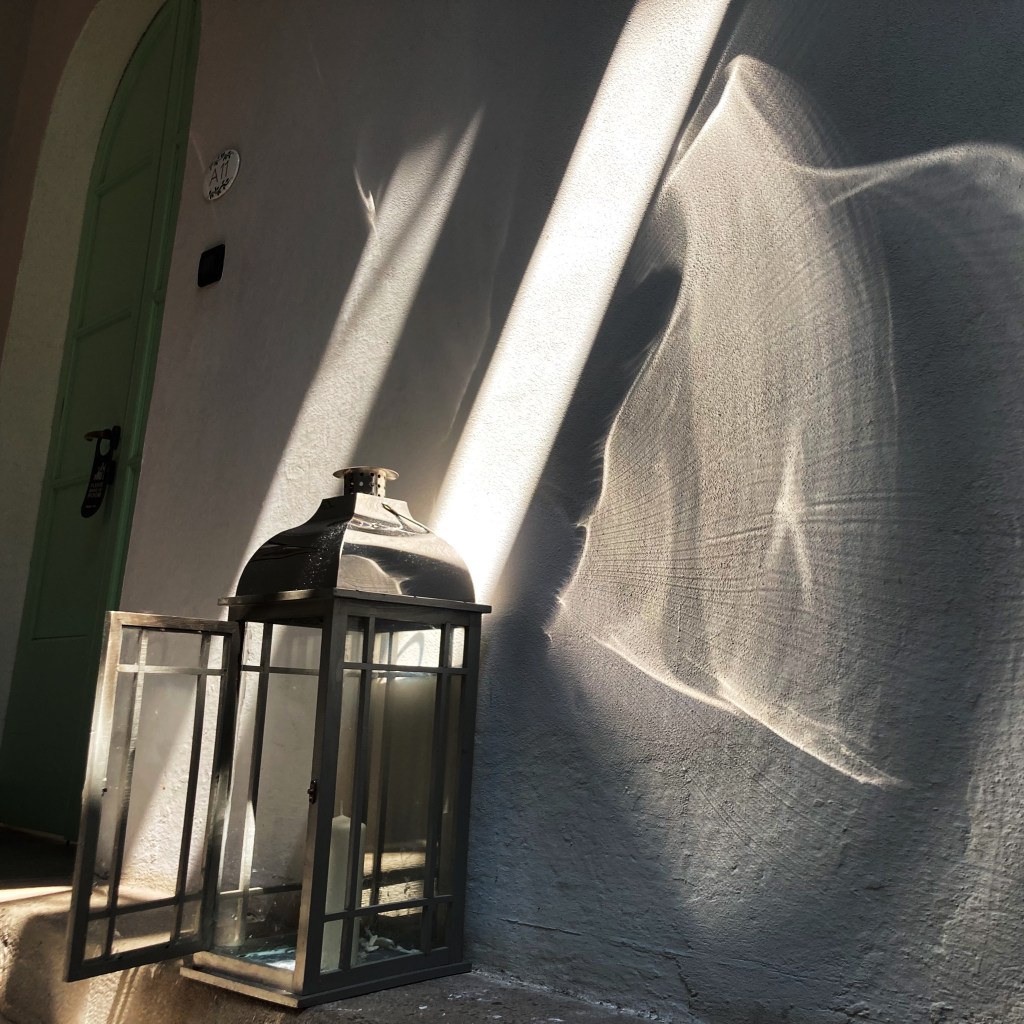 Light refracted through a the glass of metal lantern explodes onto interior stone walls.