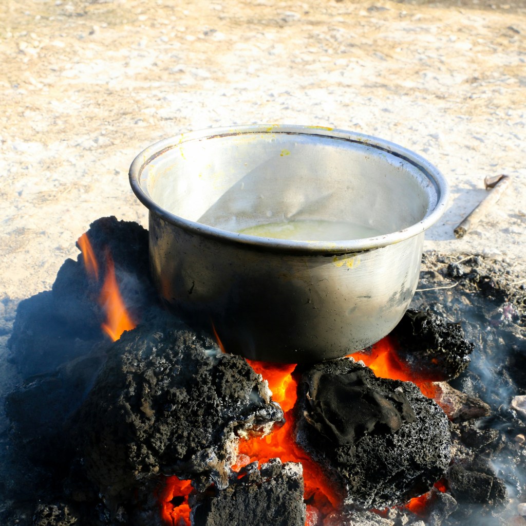 A stainless steel pot sits on top of an open fire 